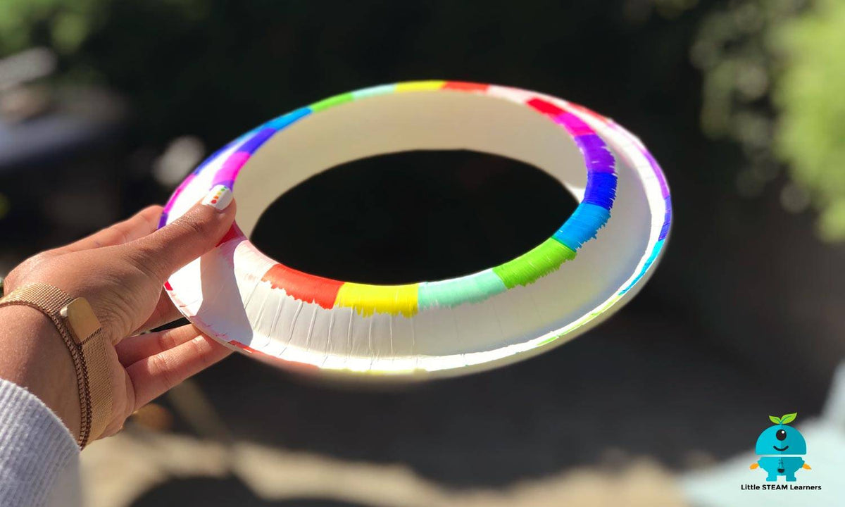 "Homemade paper plate frisbee made from two decorated paper plates taped together, forming a colorful and lightweight flying ring."