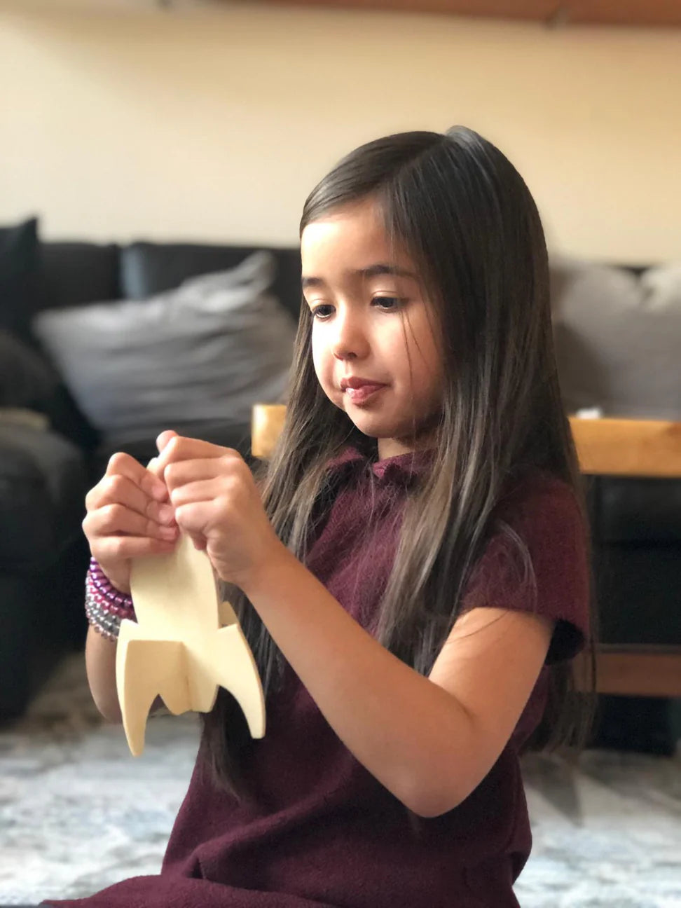 Young girl playing with a wooden toy in a living room setting