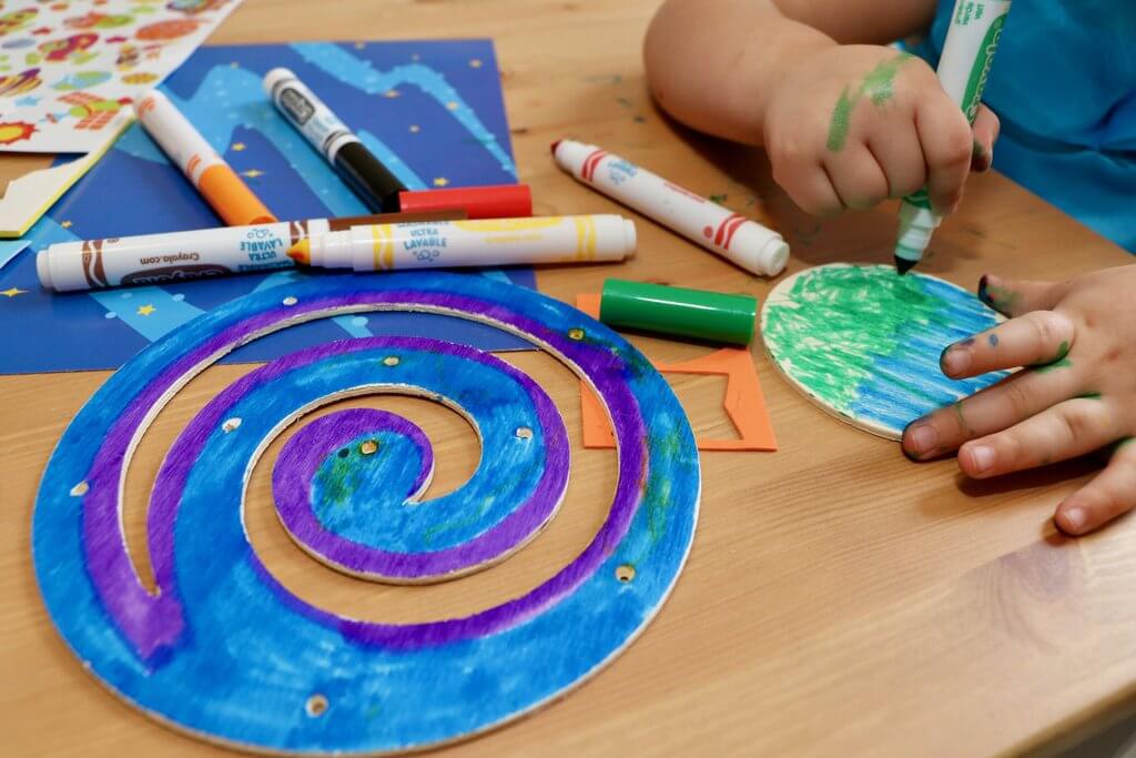 Children's hands coloring paper planets