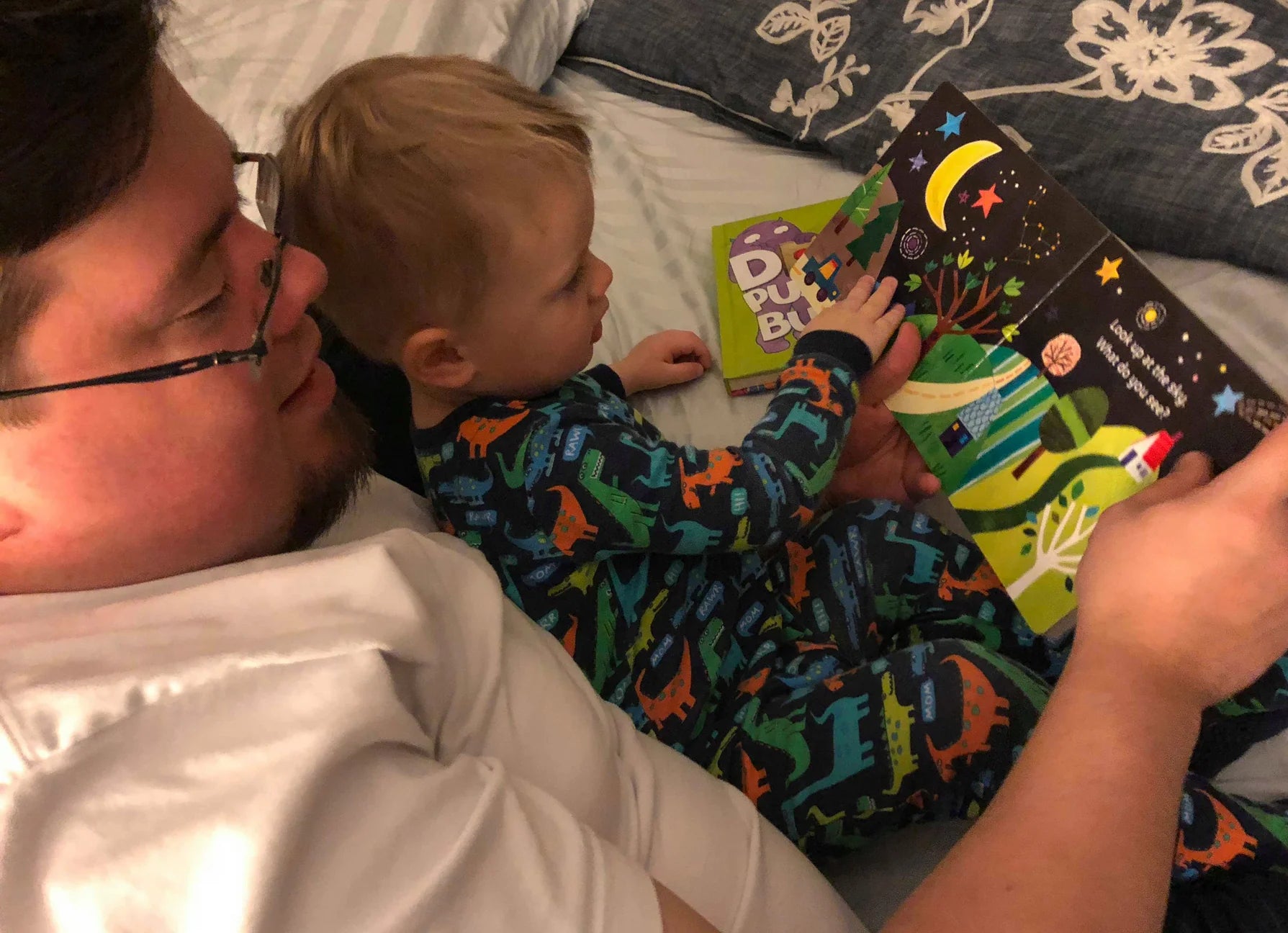 Man and child reading a book together on a bed