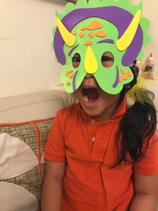Child wearing a colorful dinosaur mask indoors