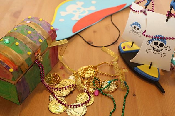 Pirate-themed craft including a treasure chest, gold coins, and a ship on a wooden surface.