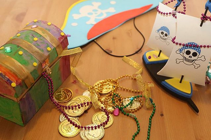 Pirate-themed craft including a treasure chest, gold coins, and a ship on a wooden surface.