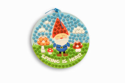 Decorative round sign with a gnome and mushrooms design, featuring 'Spring is Here' text.