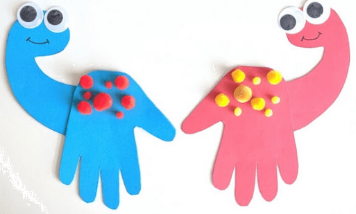 Two colorful hand-shaped dinosaur crafts with googly eyes and candy toppings on a white background.