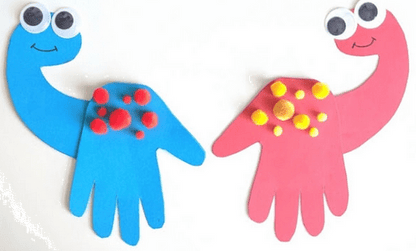 Two colorful hand-shaped dinosaur crafts with googly eyes and candy toppings on a white background.