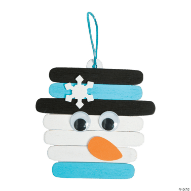 Craft stick snowman with black hat, blue scarf, white face, and orange carrot nose on a clear background.