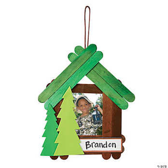 Green wooden photo frame shaped like a cabin with a picture of a child inside, on a white background.