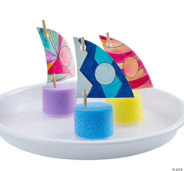 Colorful paper sailboats on foam floats on a white plate