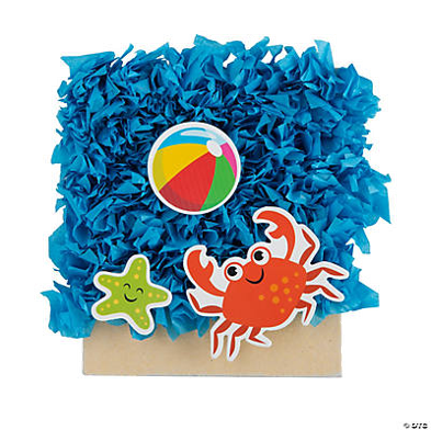 Blue tissue paper ocean with a beach ball, red crab, and green starfish with beach sand on a white background