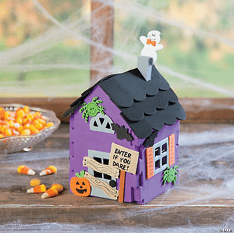 Halloween-themed decorative house with candy on a wooden surface