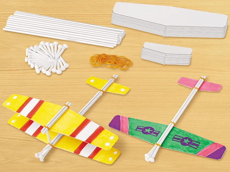 Colorful paper gliders and components on a wooden surface
