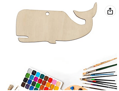Wooden whale-shaped craft board with paint, brushes, and paint palette on a white background