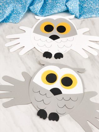 Two paper owl crafts on a white background with blue tissue paper.